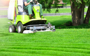Person Using A Riding Lawn Mower On Green Grass